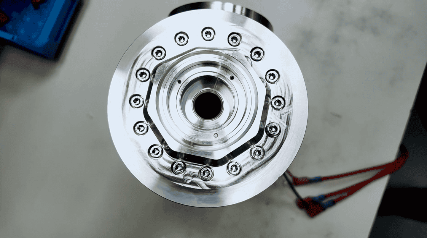 Top-down view of a high-precision CNC machined metal component for a RobCo robot, showing a circular arrangement of bolts and a polished silver finish.