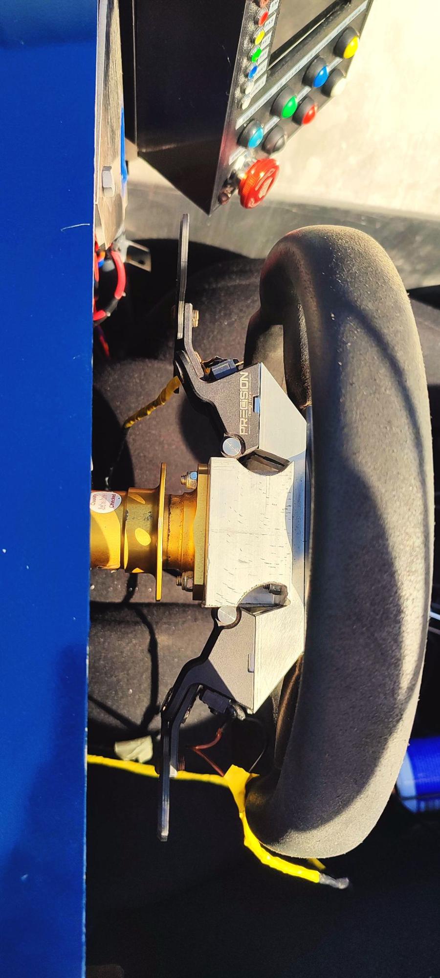 Custom-machined aluminium paddle shifter bracket installed directly behind the steering wheel
